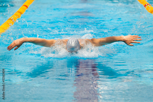 dynamic and fit swimmer in cap breathing performing the butterfly stroke © satyrenko