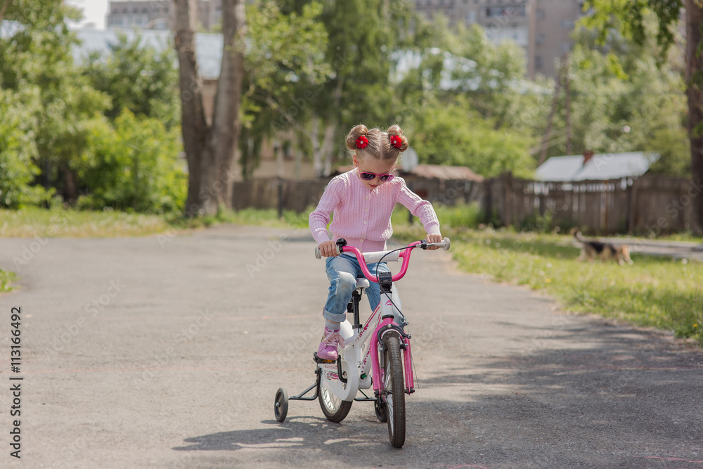 girl rides a bicycle on a warm summer track