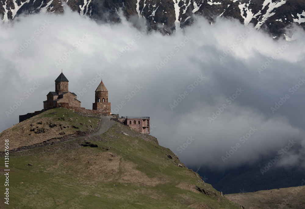 Photo Trinity church in Gergeti, against the backdrop of snowy mountains and clouds, Georgia