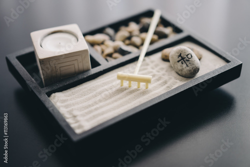Photography Zen garden with sand, rake, stones, and candle