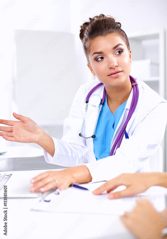 Beautiful young smiling female doctor sitting at the desk and writing. Beautiful young smiling female doctor sitting at the desk and writing.