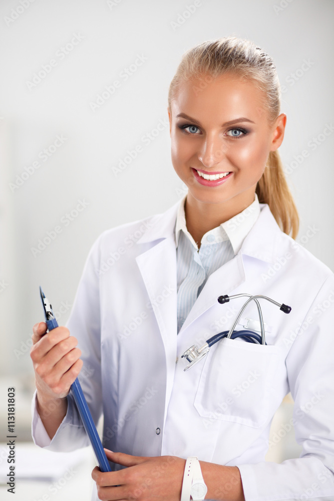 Smiling female doctor with a folder in uniform standing at hospital Smiling female doctor with a folder in uniform standing at hospital