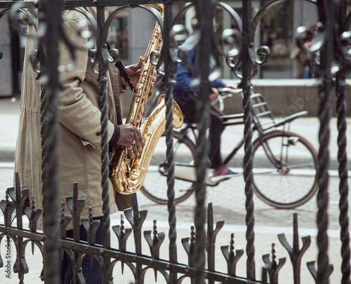 Photography african street musician playing jazz on saxophone throw lattice with bicycle sil
