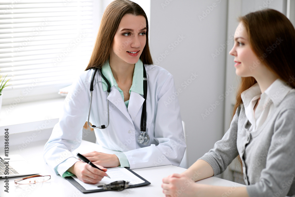 Doctor and patient sitting at the desk near the window in hospital Doctor and patient sitting at the desk near the window in hospital