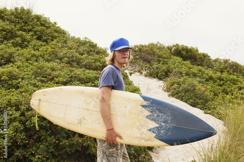 Surfer walking over dunes photo