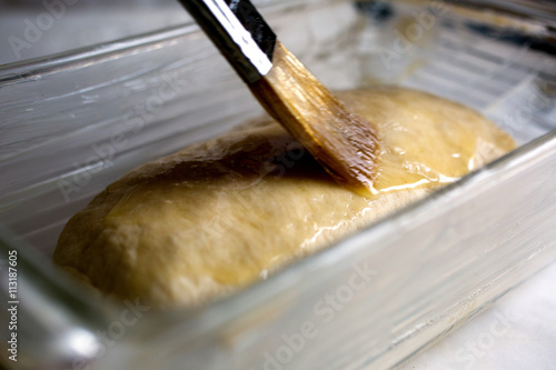 Brushing melted butter on white bread dough