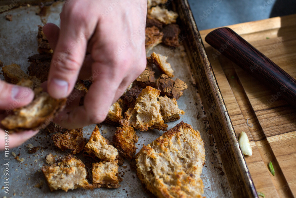 Person tearing bread on baking tray Person tearing bread on baking tray