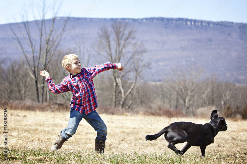 Young boy(8-9) playing fetch with dog Young boy(8-9) playing fetch with dog