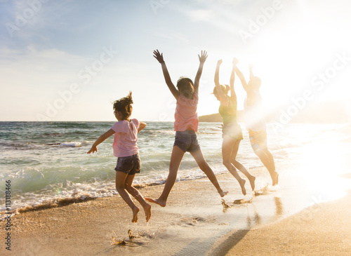 happy young family jumping on beach at sunset