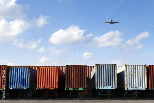 Airplane flying over row of freight containers