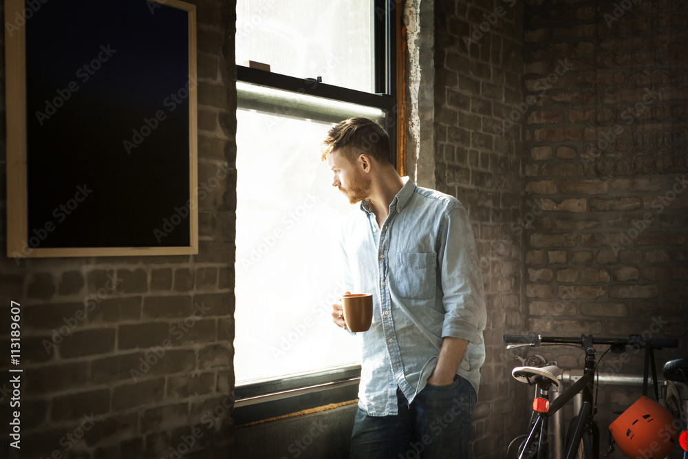 Man holding coffee mug while looking through the window Man holding coffee mug while looking through the window