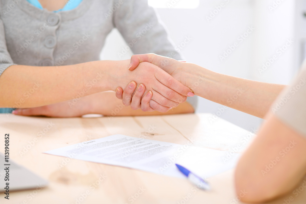 Young business woman shaking hands after signing contract Young business woman shaking hands after signing contract