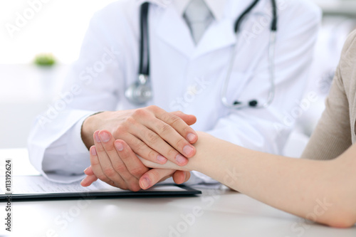 Fototapeta Naklejka Na Ścianę i Meble -  Hand of doctor reassuring her female patient
