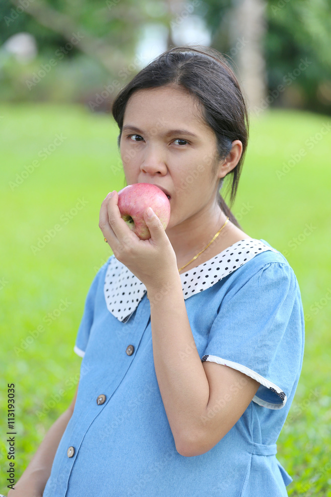 Asian pregnant women using hand catch apple up eating.