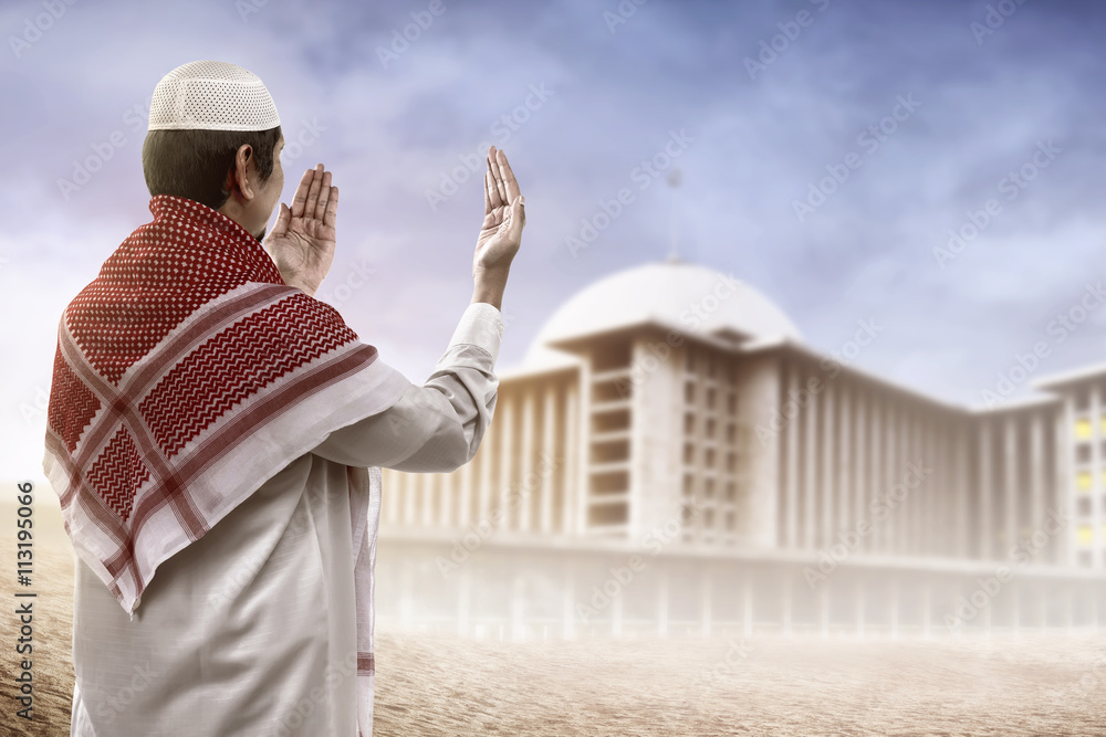 Young muslim man praying looking to mosque