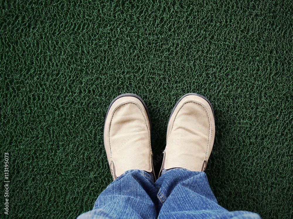 Feet wearing shoes standing on green carpet