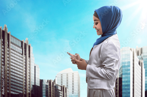 Muslim woman typing on cellphone