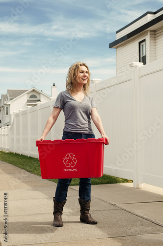 Young woman taking out recycling in neighborhood photo