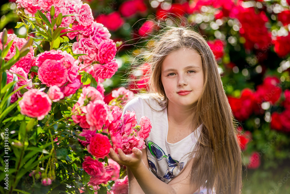 Fototapeta premium Beautiful girl standing in the park of roses.