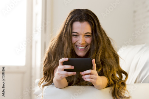 young beautiful girl at home couch relaxed using mobile phone smiling happy and cheerful
