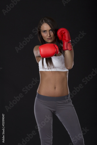 Beautiful long dark hair kick box girl with red gloves on her hands 