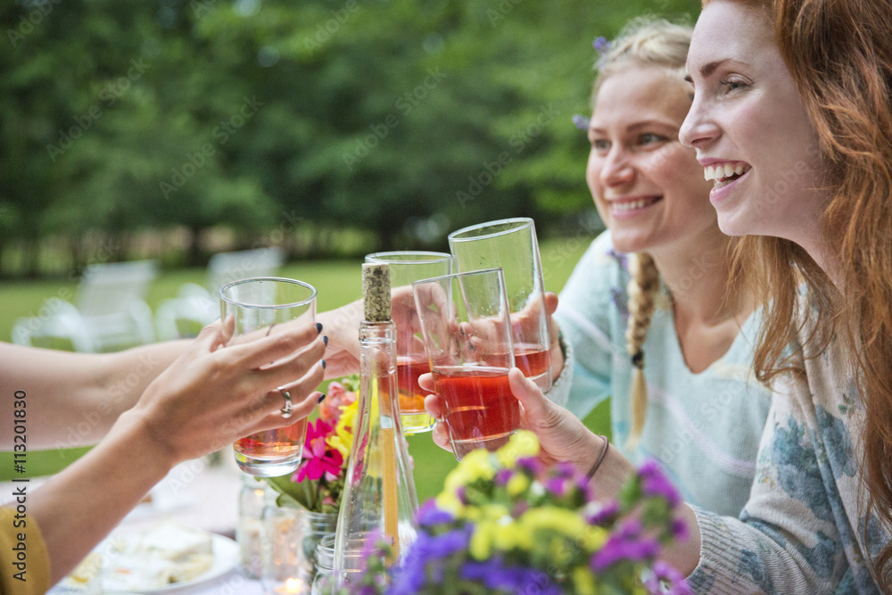 Happy friends toasting drinks while sitting at breakfast table in backyard Happy friends toasting drinks while sitting at breakfast table in backyard