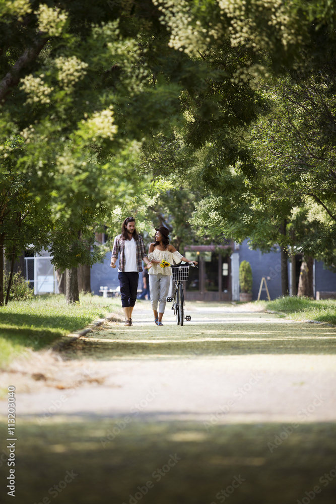 Couple talking while walking with bicycle on footpath at park Couple talking while walking with bicycle on footpath at park