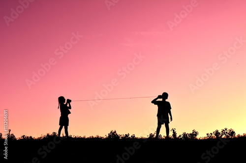 Silhouette children playing string phone