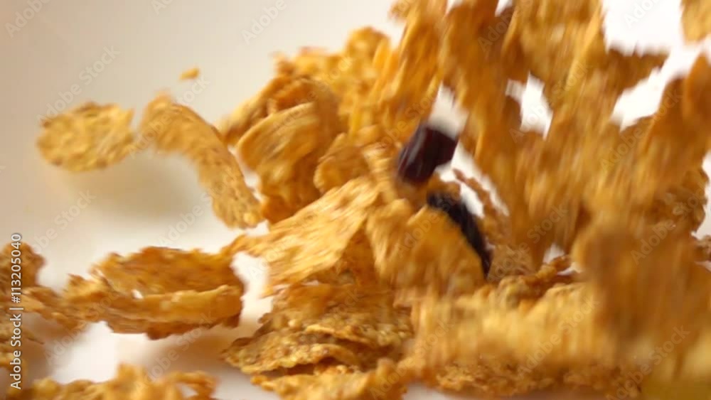 Golden corn flakes scattering on white plate macro super slow motion shot Golden corn flakes scattering on white plate macro super slow motion shot