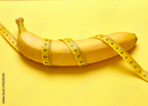 Isolated banana with measuring tape on a yellow background