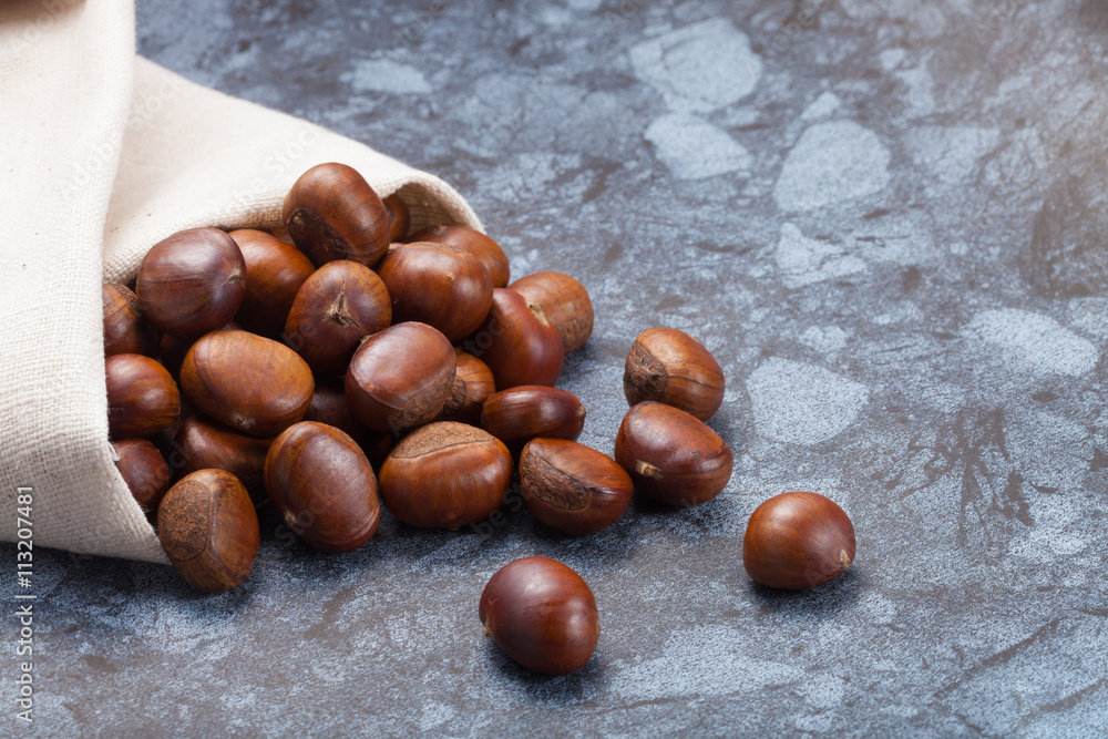 Obraz premium Horizontal image of a pile of chestnuts on stone texture floor with copy space