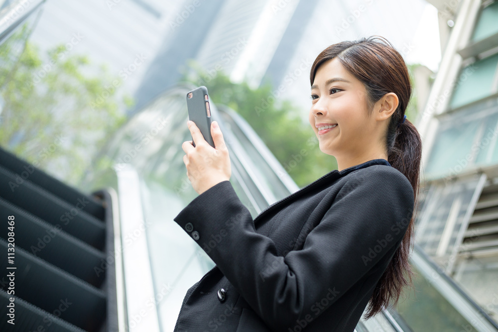 Business woman use of phone and standing on escalator Business woman use of phone and standing on escalator