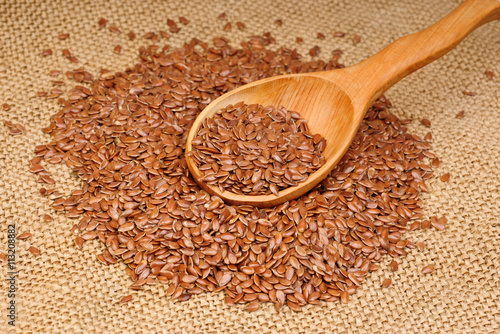 close up of flax seeds in wooden spoon on canvas  background