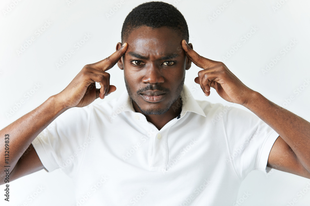 Portrait of sad unhappy African man having bad headache, looking at the camera with painful expression, holding hands on his temples. Human face expressions, emotions and feelings. Body language Portrait of sad unhappy African man having bad headache, looking at the camera with painful expression, holding hands on his temples. Human face expressions, emotions and feelings. Body language