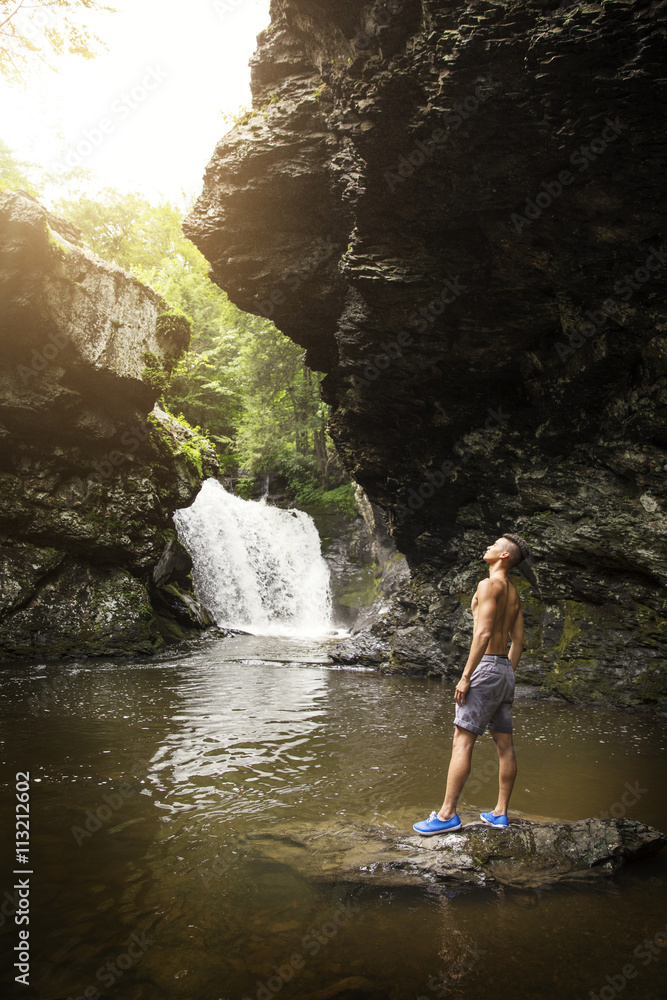 Man looking up while standing on rock in lake Man looking up while standing on rock in lake