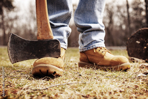 Low section of lumberjack with pick axe on field