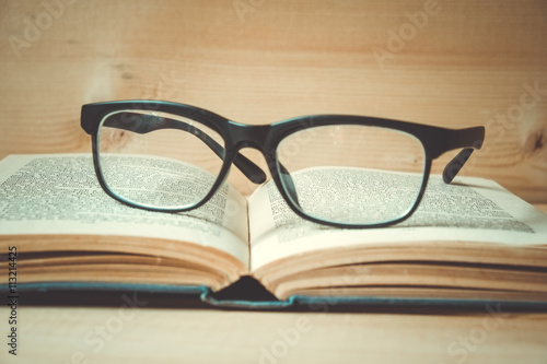 Old books and glasses on a wooden table with filter effect retro