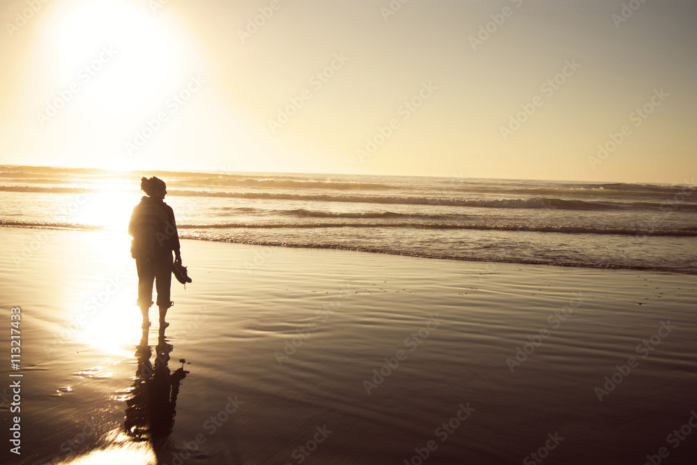 Rear view of traveler standing at beach against clear sky during sunset Rear view of traveler standing at beach against clear sky during sunset