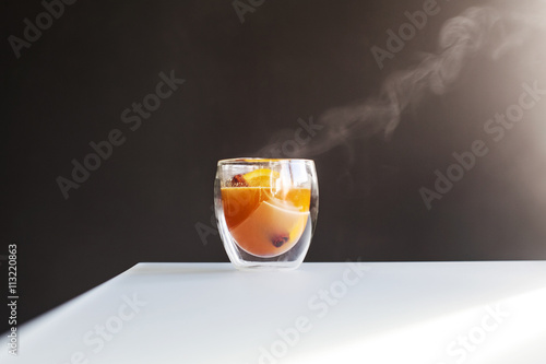 A steaming hot cup of apple cider with an apple slice and cinnamon stick photo