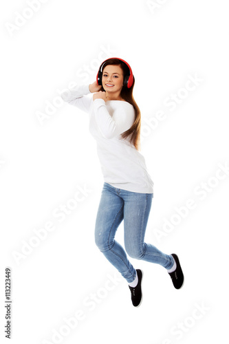 Beautiful young woman jumping and listen music