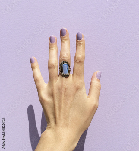 Woman's hand with ring against purple wall