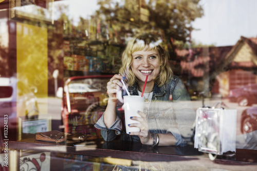 Woman behind window drinking milkshake photo