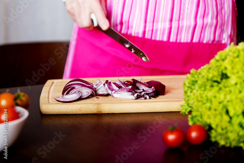 Woman cut red onion on cutting board photo