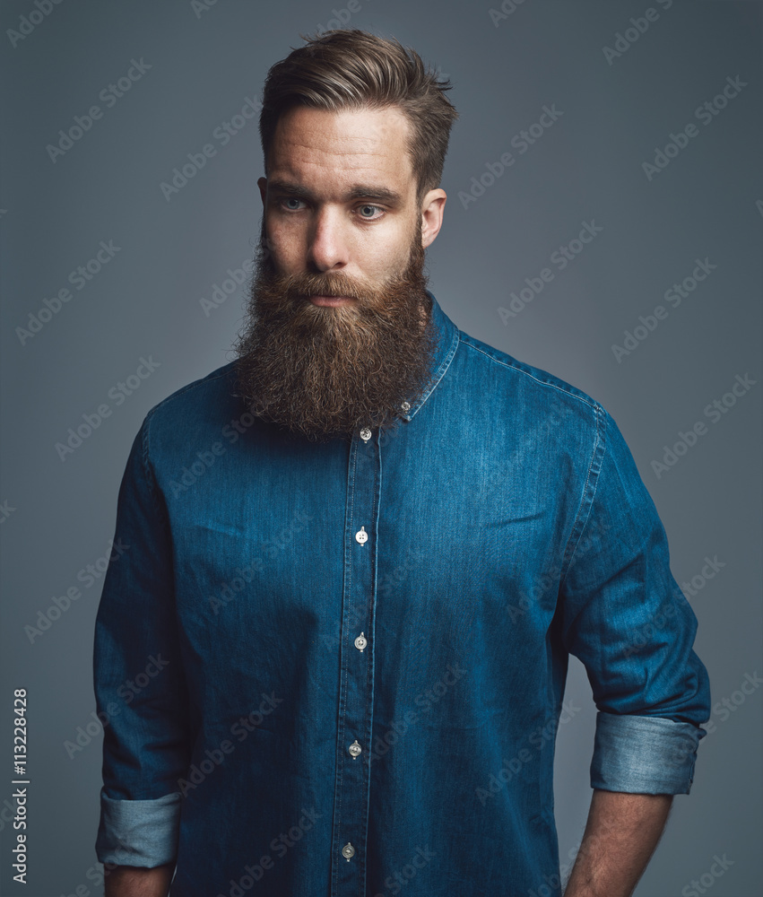 Bearded man in blue denim with serious expression Bearded man in blue denim with serious expression