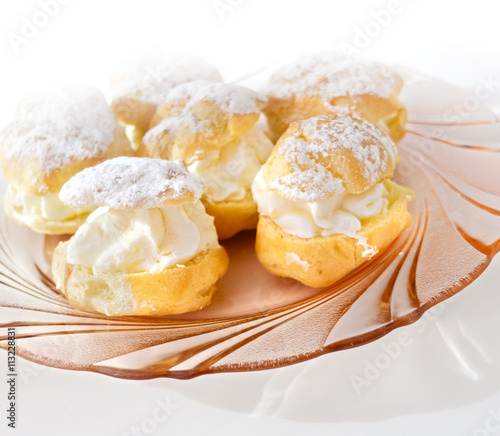 Cream puff or profiterole with filling and powdered sugar topping, isolated, against white background