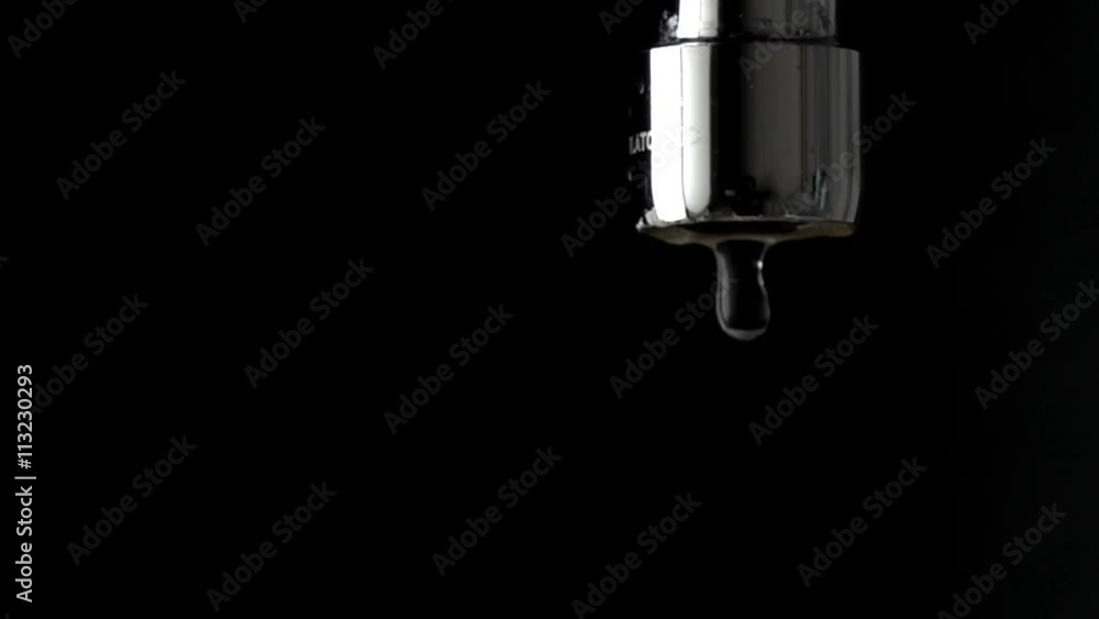 Macro slow motion shot of dripping chrome water tap against black background Macro slow motion shot of dripping chrome water tap against black background