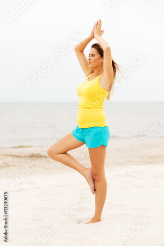 Young woman making yoga exercises on the beach