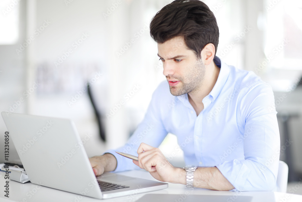 Young professional business man working on laptop at office Young professional business man working on laptop at office