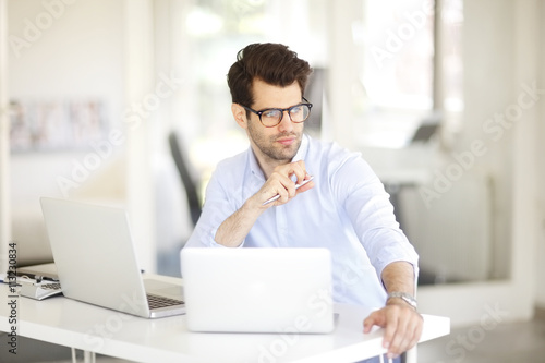 Young professional business man working on laptop at office