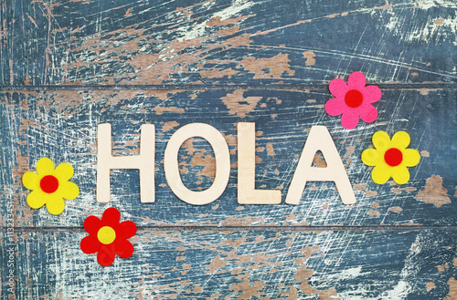 Hola (hello in Spanish) written with wooden letters on rustic surface
